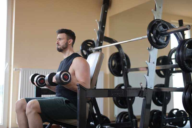 sitting man lifting dumbbells