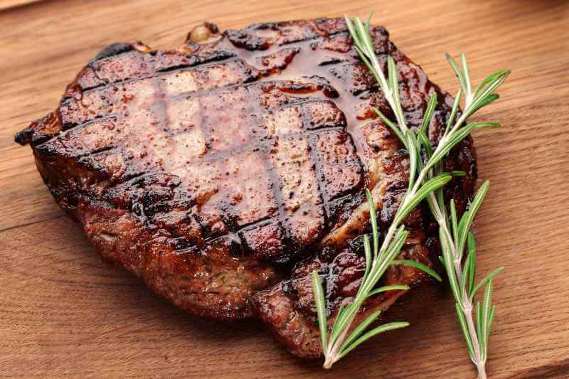 juicy beef steak with grill marks and rosemary on the side