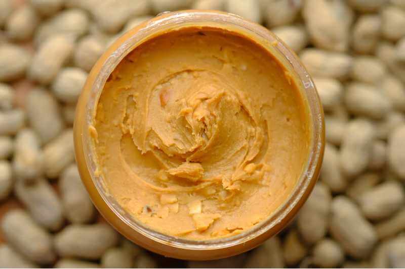 top view of peanut butter with peanuts as background