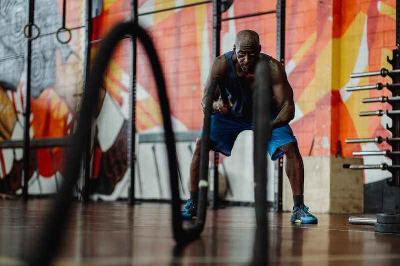 man in the gym using battle rope