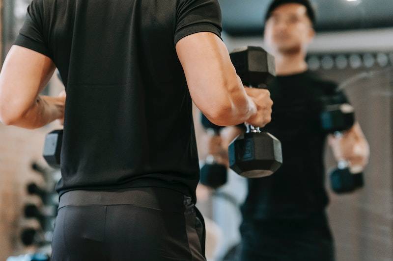 man standing in front of a mirror lifting dumbbells