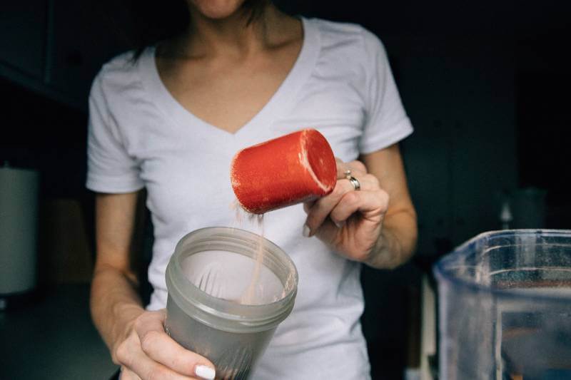 woman pouring protein shake into a cup