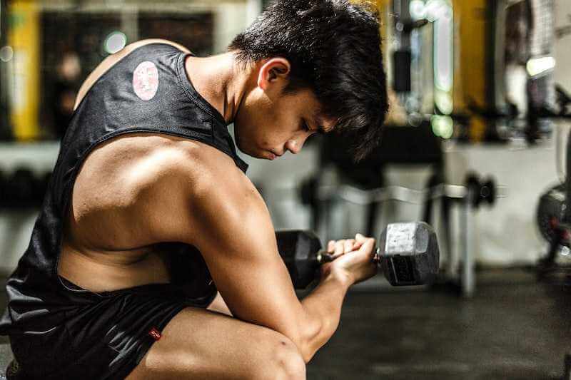 man working out his arm muscles using dumbbells