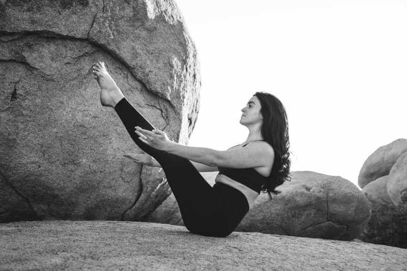 woman doing yoga boat pose outdoors