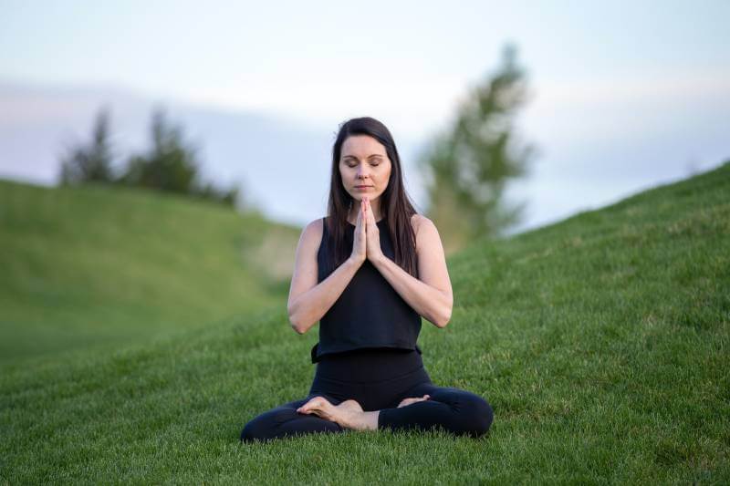 woman sitting on the grass and doing meditation