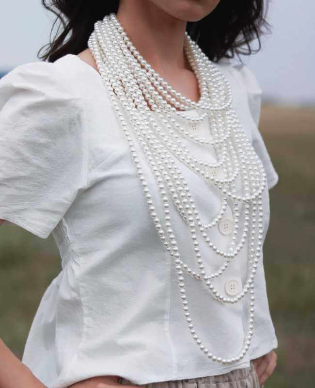 woman wearing white top and pearls