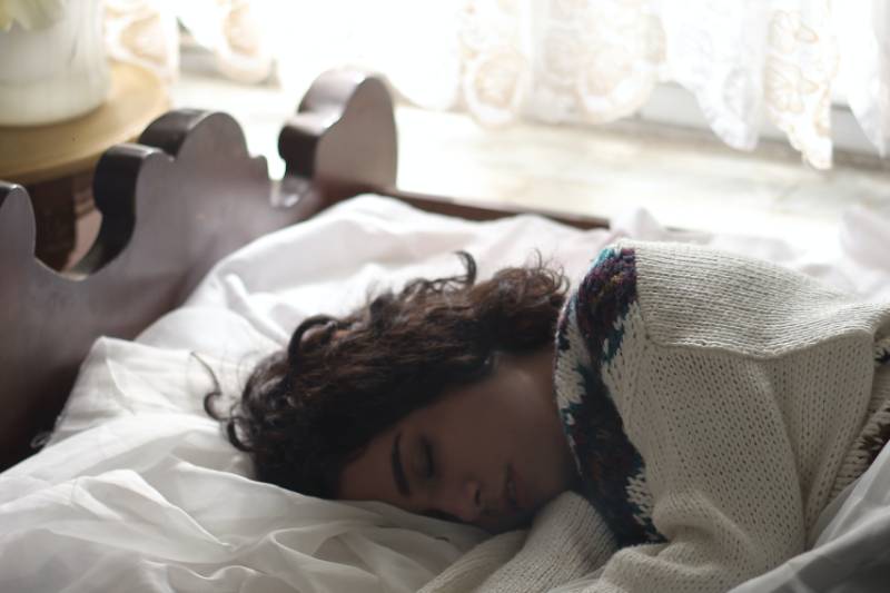 woman in sweater sleeping on the bed